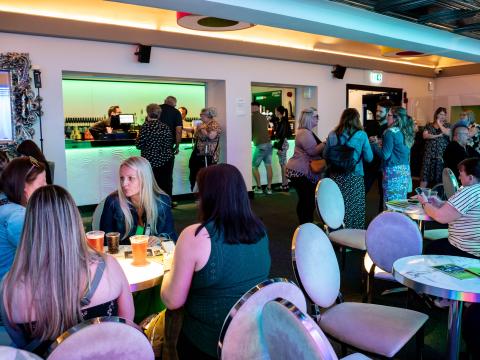 Bar area in The Studio Bradford with people sat at tables having a drink and chatting.